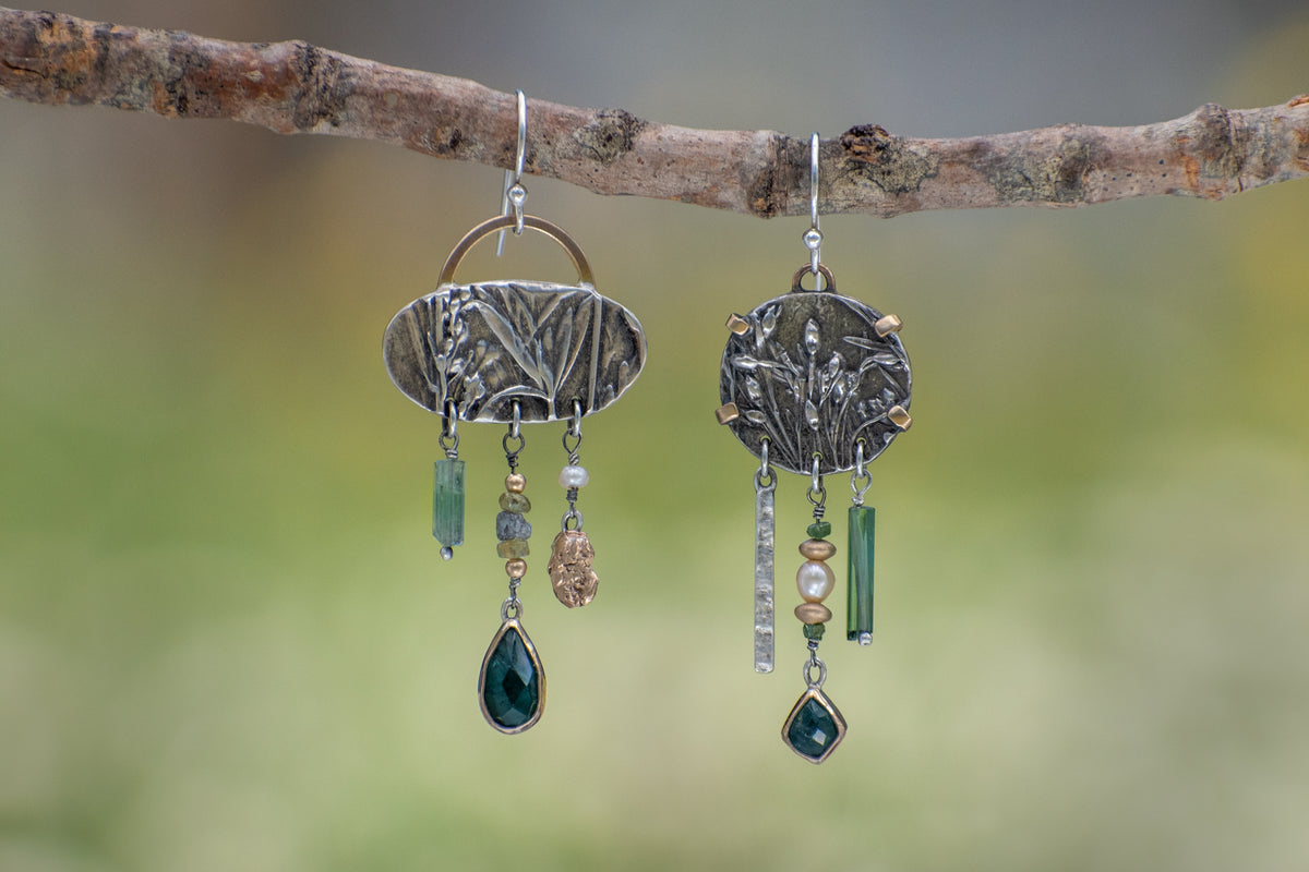 Asymmetrical sterling silver and 14k gold Wild Meadow Earrings with botanical textures and dangling green tourmaline, aquamarine, rough diamond and pearl details.