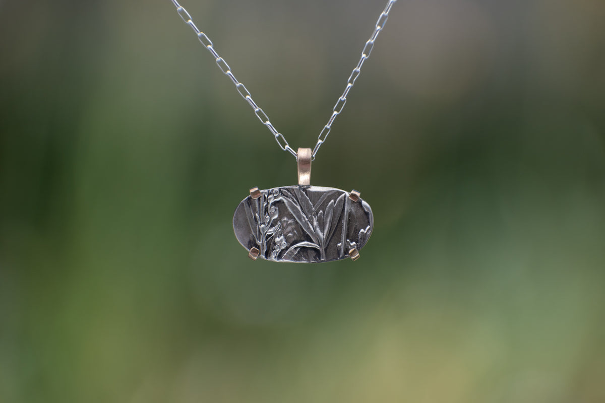 Nature-inspired Horizontal Wild Meadow Necklace in oxidized sterling silver and 14k gold with wildflower and botanical textures from lupine leaves and late-summer sagebrush buds.