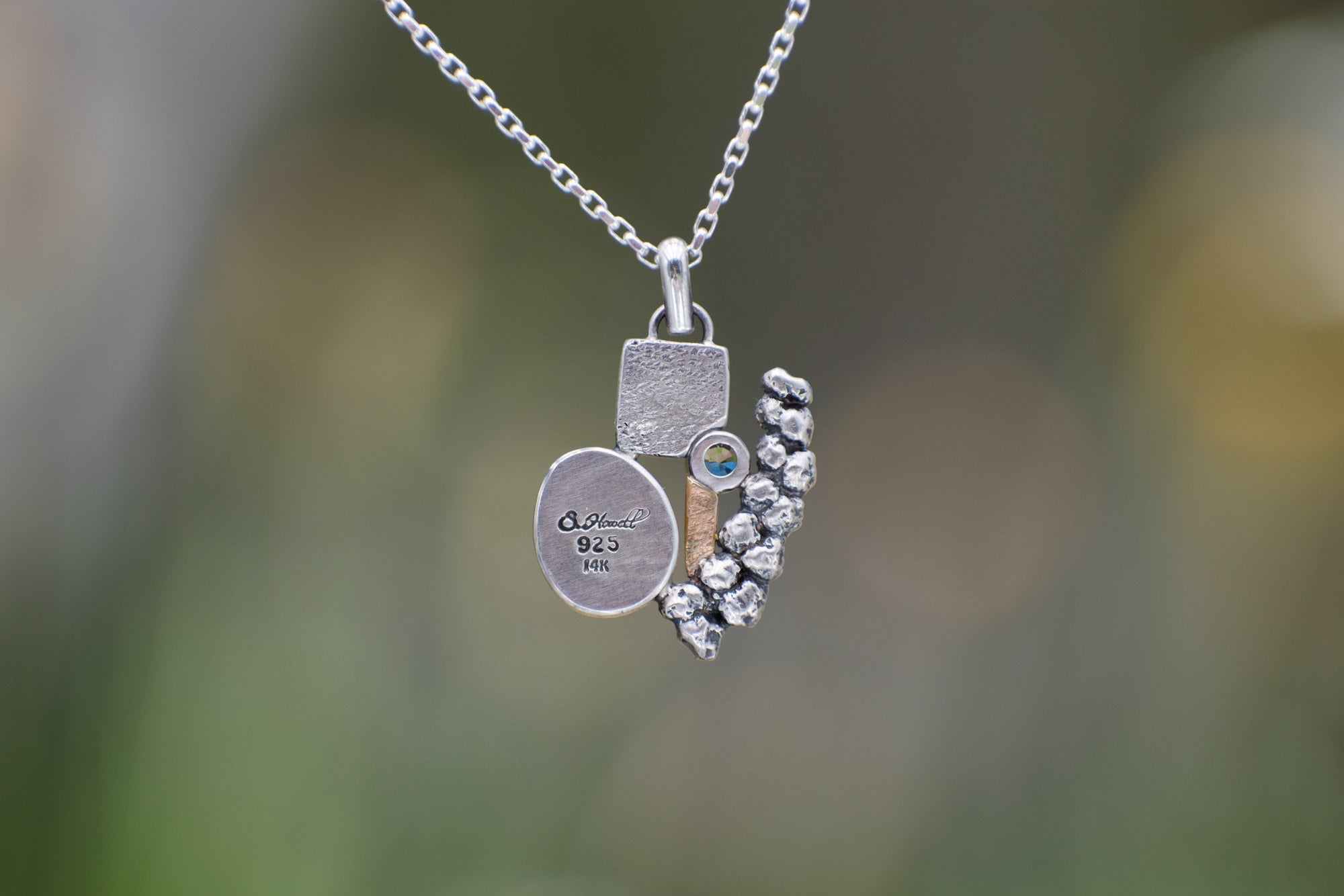 Nature-inspired Wild Meadow Cluster Necklace in sterling silver and 14k gold with sensitive fern botanical texture and two green sapphire gemstones.