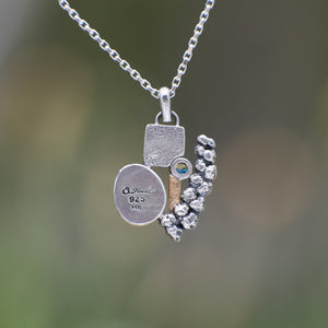 Nature-inspired Wild Meadow Cluster Necklace in sterling silver and 14k gold with sensitive fern botanical texture and two green sapphire gemstones.