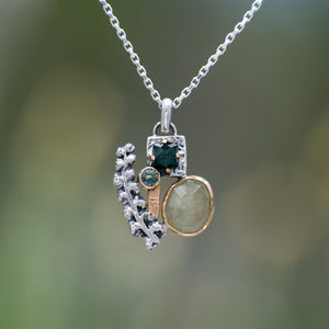 Nature-inspired Wild Meadow Cluster Necklace in sterling silver and 14k gold with sensitive fern botanical texture and two green sapphire gemstones.