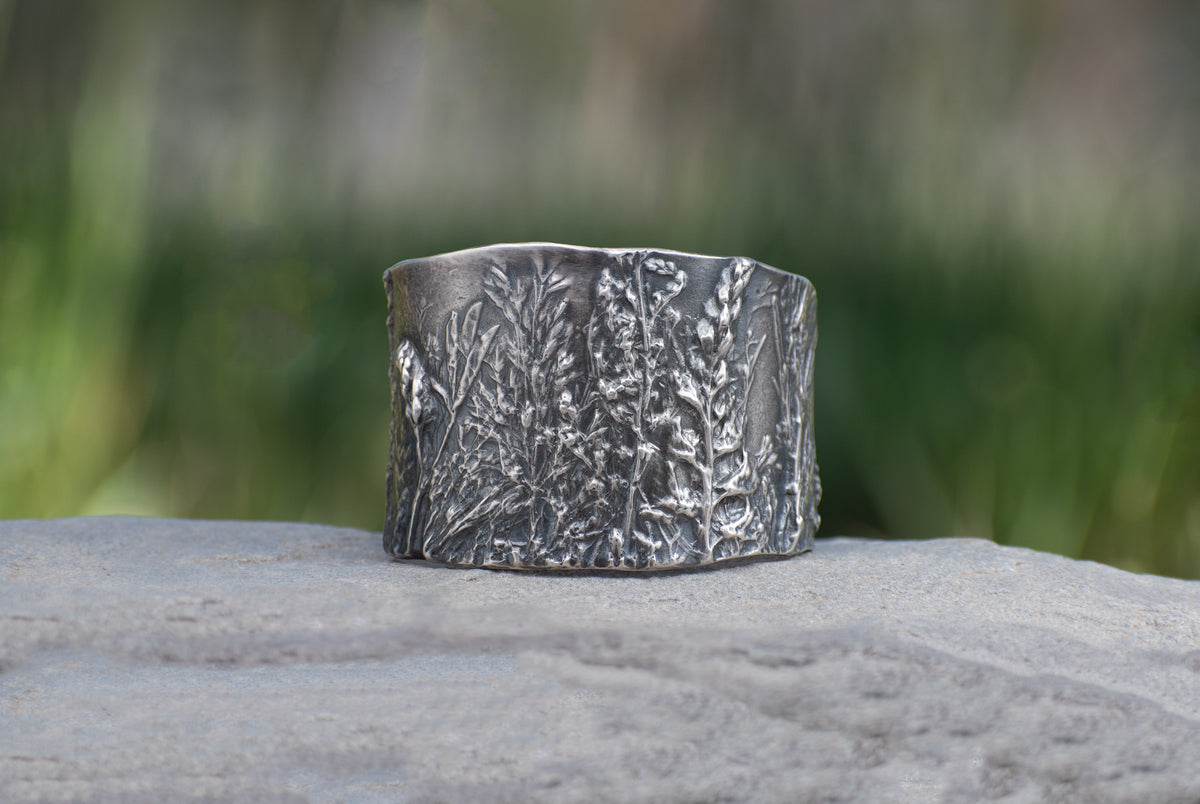 Nature-inspired Wild Meadow Cuff in oxidized sterling silver with layered wildflower and botanical textures from lupine, late-summer sagebrush, goldenrod and wild grasses.