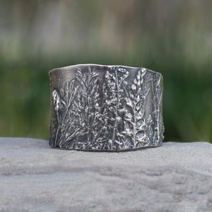Nature-inspired Wild Meadow Cuff in oxidized sterling silver with layered wildflower and botanical textures from lupine, late-summer sagebrush, goldenrod and wild grasses.