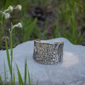 Nature-inspired Wild Meadow Cuff in oxidized sterling silver with layered wildflower and botanical textures from lupine, late-summer sagebrush, goldenrod and wild grasses.