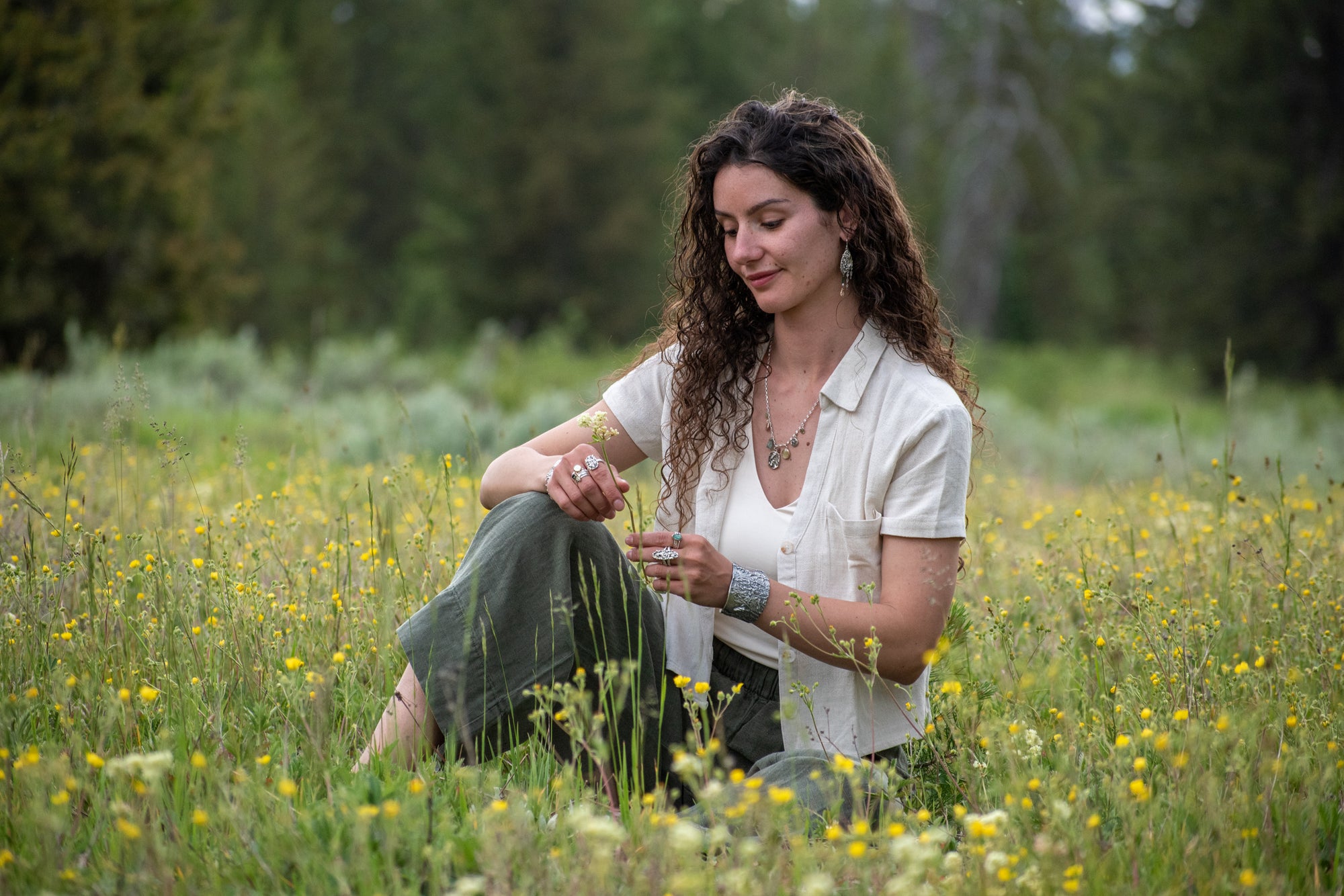 Model wearing Wild Meadow Wing Earrings in sterling silver and 14k gold with lupine, goldenrod and sage botanical textures, dangling tourmaline, kyanite, aquamarine, green garnet, green diamond and freshwater pearl gemstones.