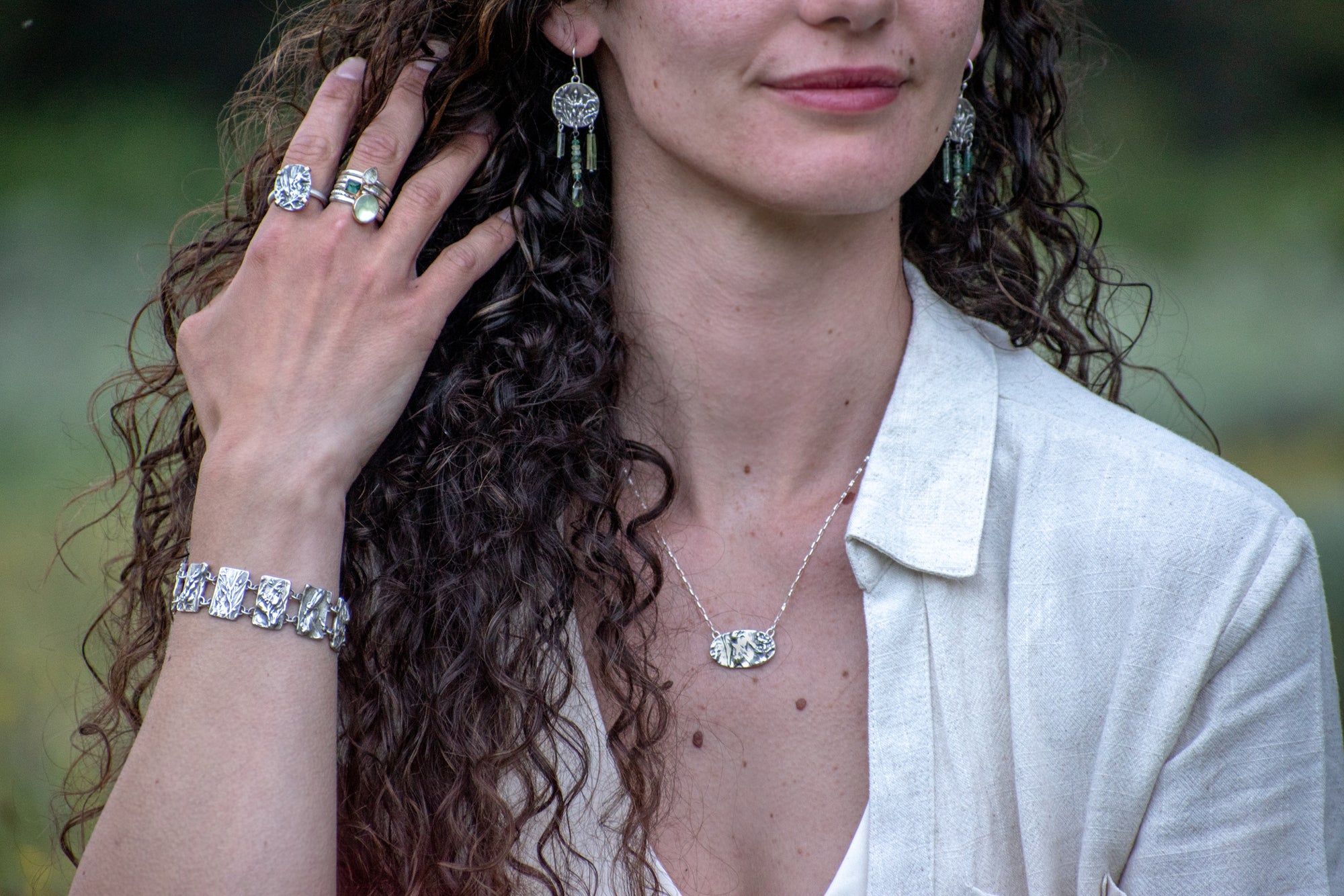 model wearing Nature-inspired Wild Meadow Bracelet in oxidized sterling silver with linked botanical panels featuring layered wildflower textures from lupine, sagebrush, goldenrod and wild grasses.