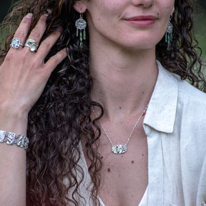 model wearing Nature-inspired Wild Meadow Bracelet in oxidized sterling silver with linked botanical panels featuring layered wildflower textures from lupine, sagebrush, goldenrod and wild grasses.