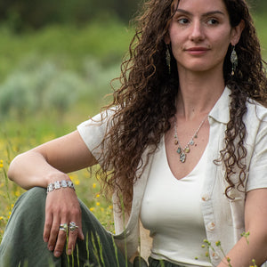 model wearing Nature-inspired Wild Meadow Bracelet in oxidized sterling silver with linked botanical panels featuring layered wildflower textures from lupine, sagebrush, goldenrod and wild grasses.