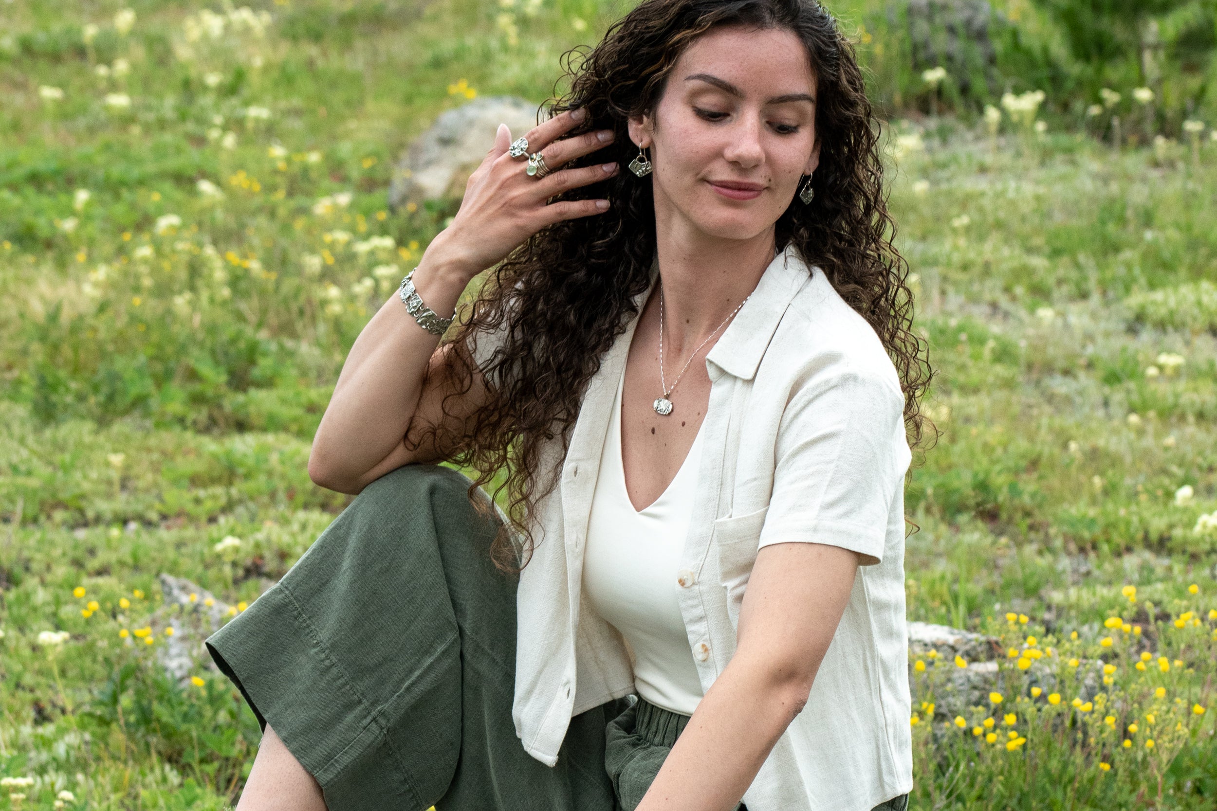 Model wearing Nature-inspired sterling silver Wild Meadow Earrings with wildflower and botanical textures from Spreading Groundsmoke and goldenrod, accented with 14k gold setting-sun arcs.