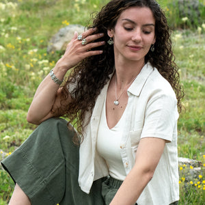 Model wearing Nature-inspired sterling silver Wild Meadow Earrings with wildflower and botanical textures from Spreading Groundsmoke and goldenrod, accented with 14k gold setting-sun arcs.