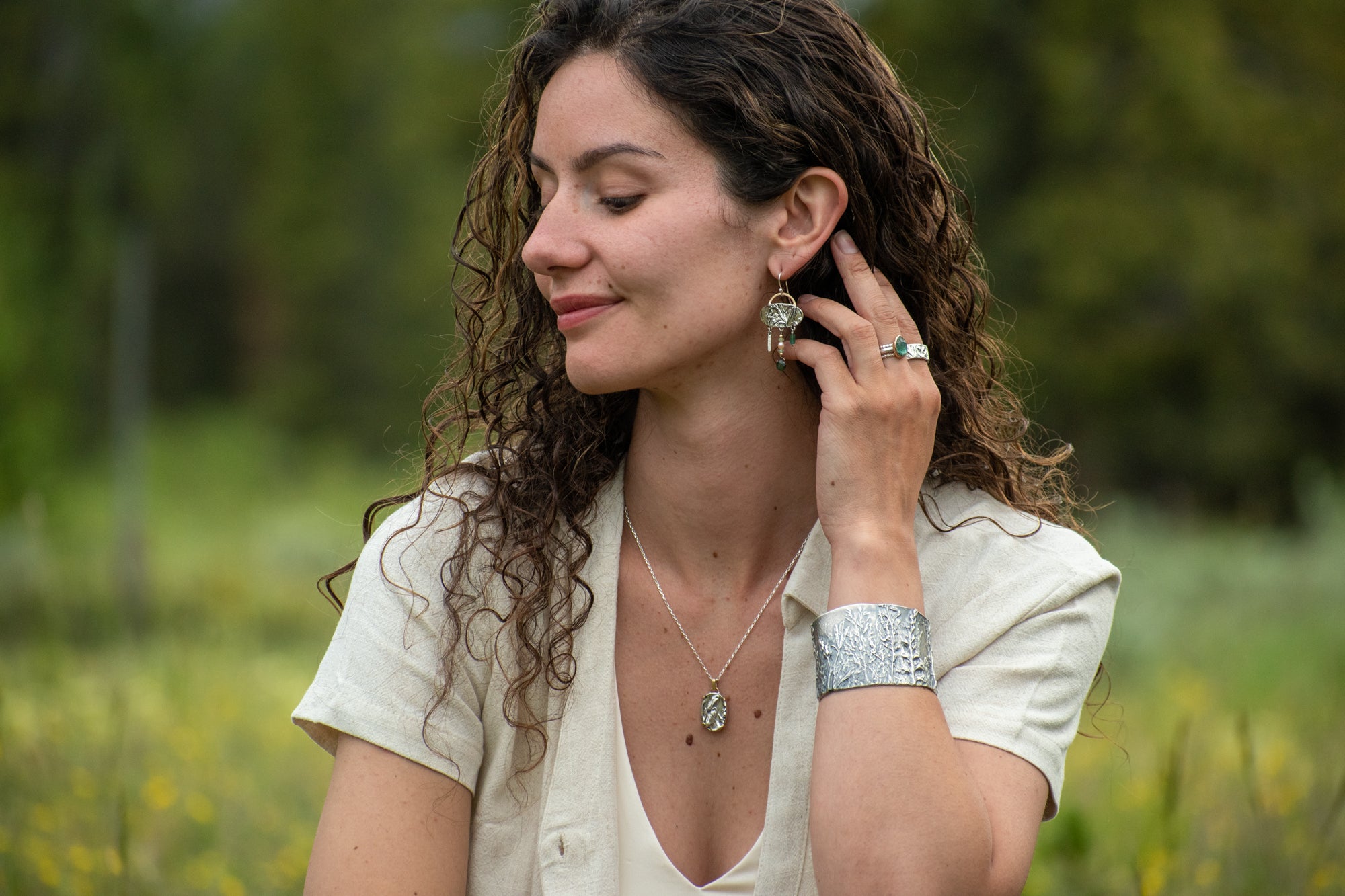 model wearing Nature-inspired Wild Meadow Ring Band in oxidized sterling silver with layered wildflower and botanical textures from budding sage, sage leaves and goldenrod.