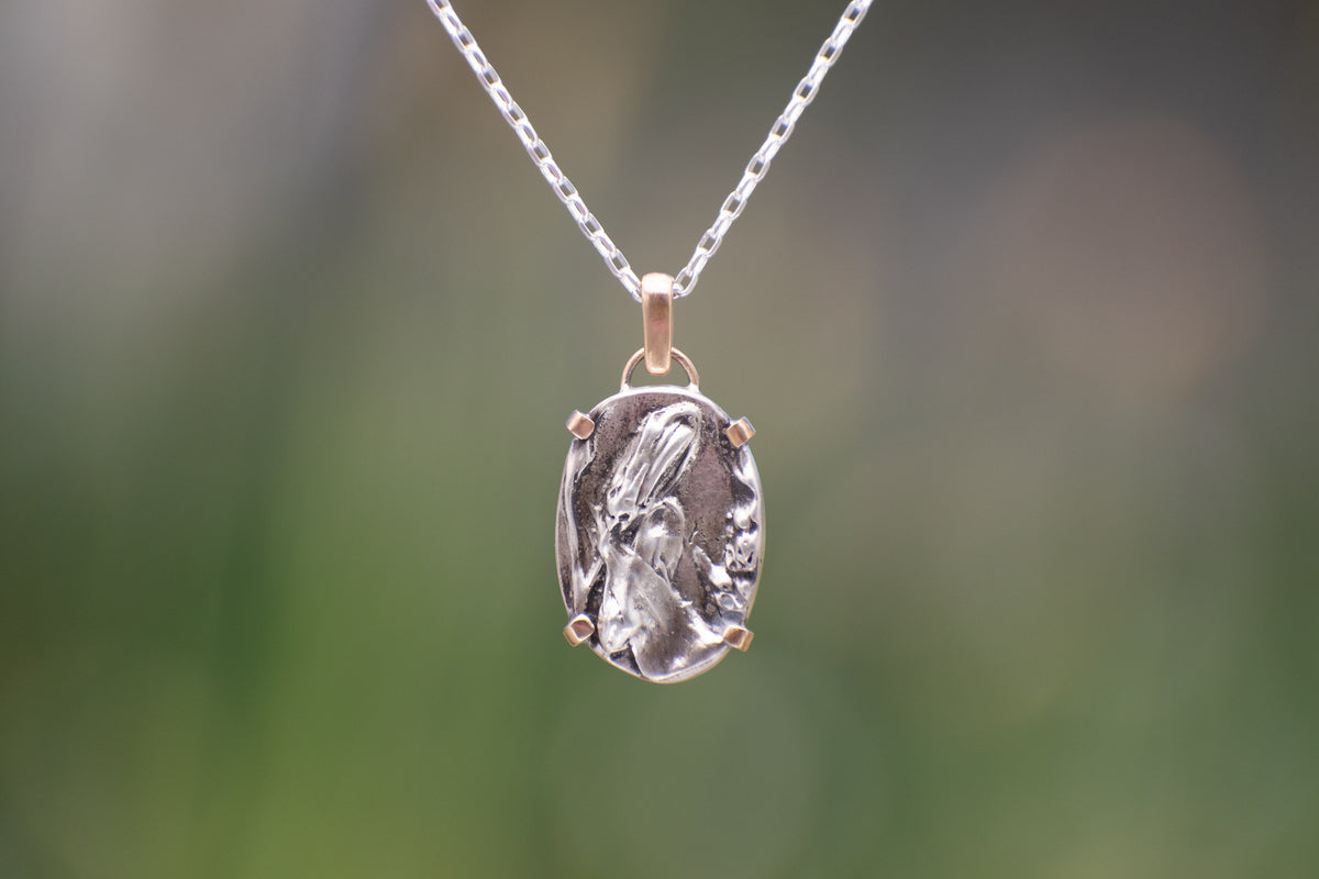 Nature-inspired Oval Wild Meadow Necklace in sterling silver and 14k gold with harebell bud and leaf botanical textures inspired by wildflowers and meadow plants.