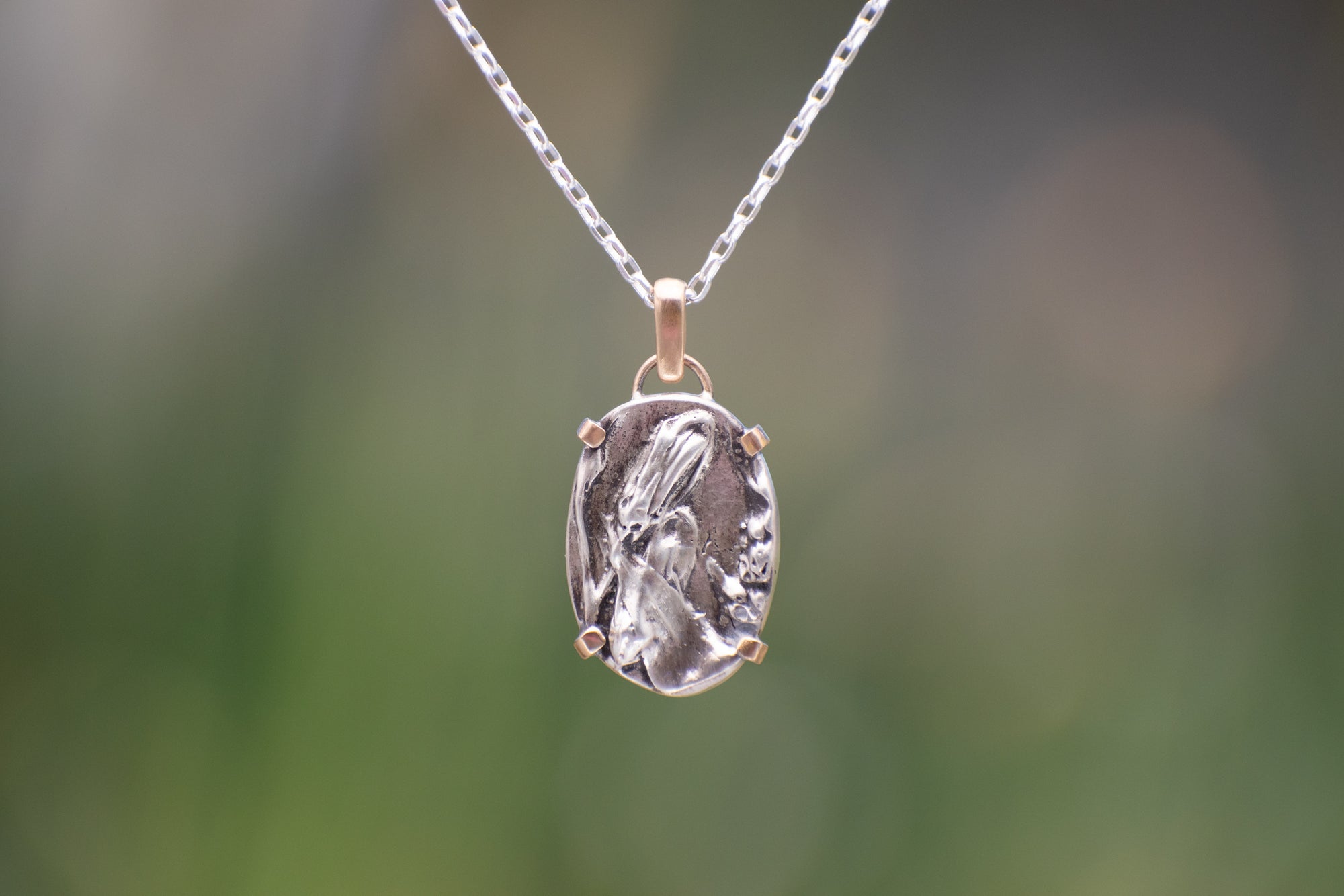 Nature-inspired Oval Wild Meadow Necklace in sterling silver and 14k gold with harebell bud and leaf botanical textures inspired by wildflowers and meadow plants.