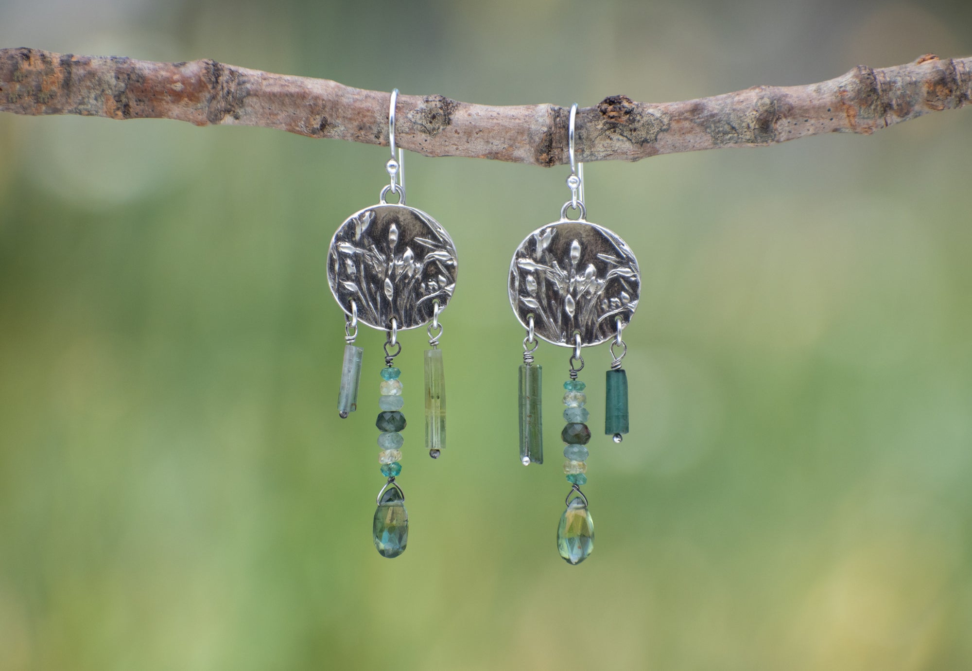 Round Wild Meadow Earrings in sterling silver with Spreading Groundsmoke botanical textures and dangling tourmaline, aquamarine, green rutile, emerald, green garnet and kyanite gemstones.