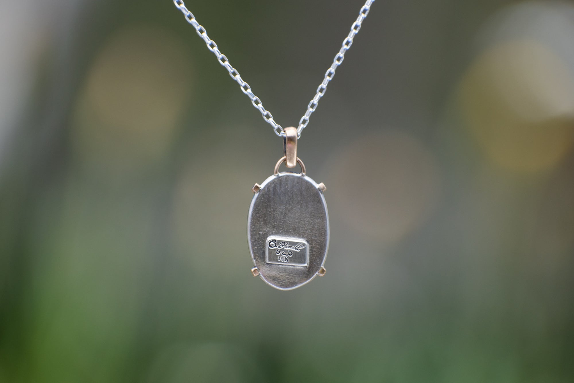 Nature-inspired Oval Wild Meadow Necklace in sterling silver and 14k gold with harebell bud and leaf botanical textures inspired by wildflowers and meadow plants.
