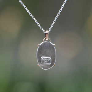 Nature-inspired Oval Wild Meadow Necklace in sterling silver and 14k gold with harebell bud and leaf botanical textures inspired by wildflowers and meadow plants.