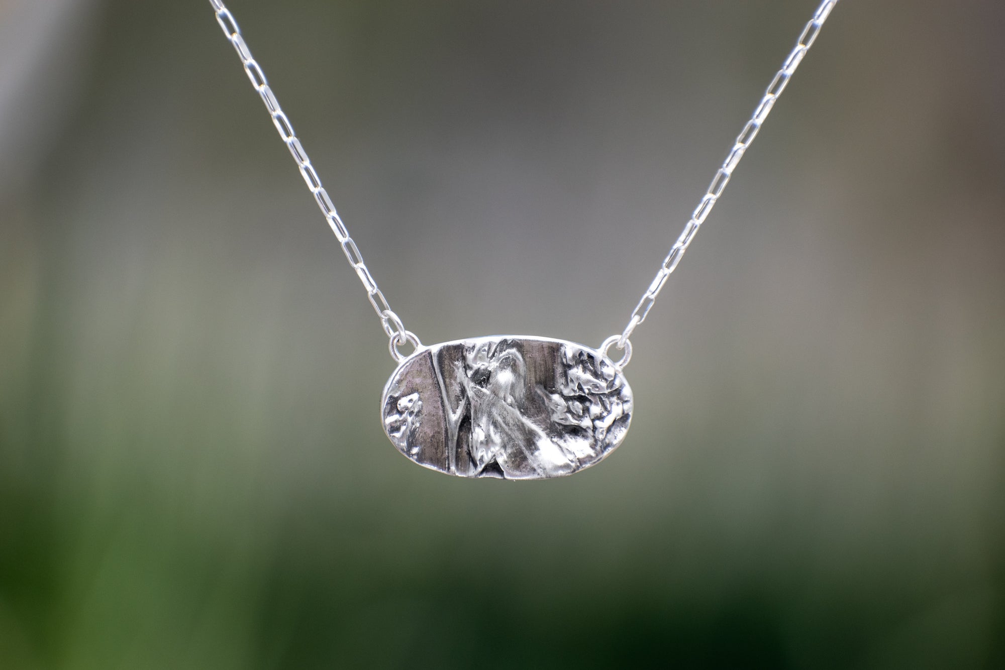 Nature-inspired Wild Meadow Necklace in oxidized sterling silver with layered wildflower and botanical textures from harebell buds, goldenrod and overlapping leaves.