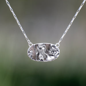 Nature-inspired Wild Meadow Necklace in oxidized sterling silver with layered wildflower and botanical textures from harebell buds, goldenrod and overlapping leaves.