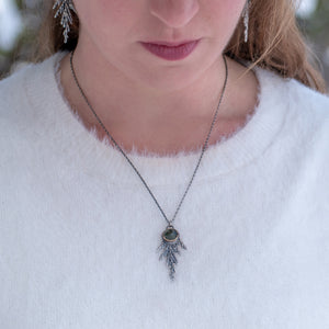 Woman wearing handmade sterling silver cedar necklace with green rutile stone set in 14k gold
